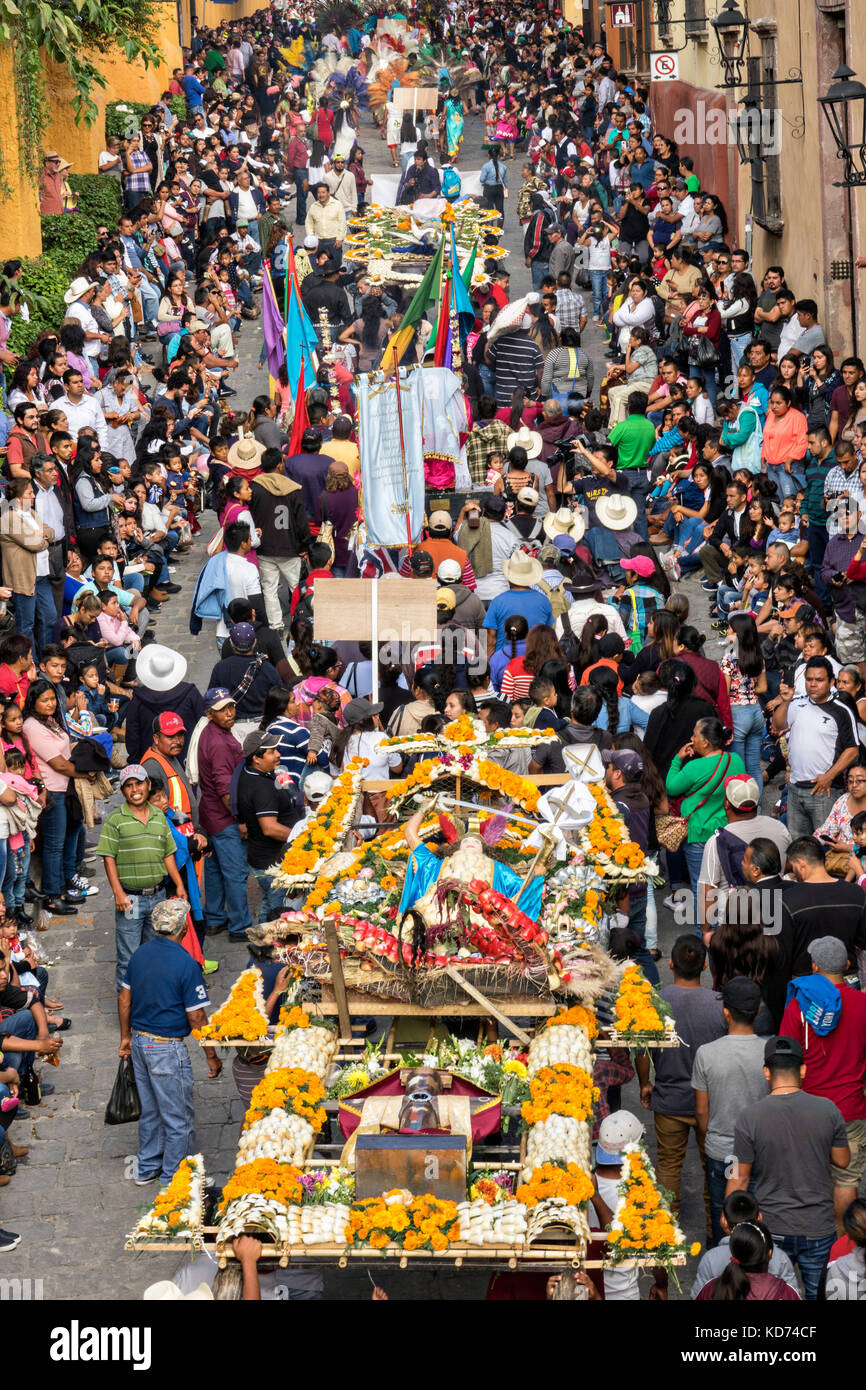 A religious procession carrying a xuchile dedicated to St Michael through the historic district during the week long fiesta of the patron saint Saint Michael September 30, 2017 in San Miguel de Allende, Mexico. Xuchiles is a offering made from woven bamboo and flowers and decorated by the native people of Mexico. Stock Photo