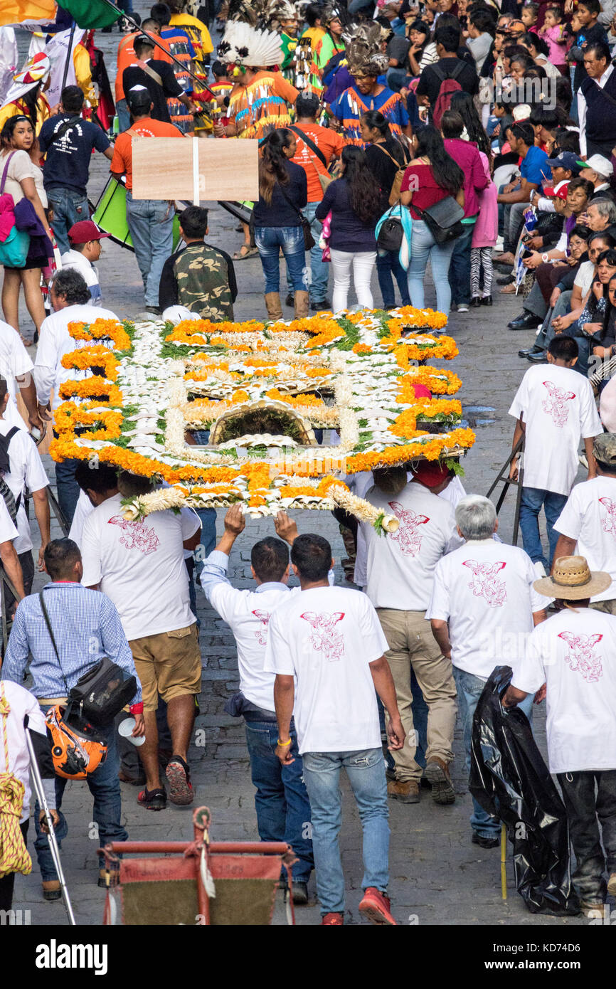 A religious procession carrying a xuchile dedicated to St Michael through the historic district during the week long fiesta of the patron saint Saint Michael September 30, 2017 in San Miguel de Allende, Mexico. Xuchiles is a offering made from woven bamboo and flowers and decorated by the native people of Mexico. Stock Photo