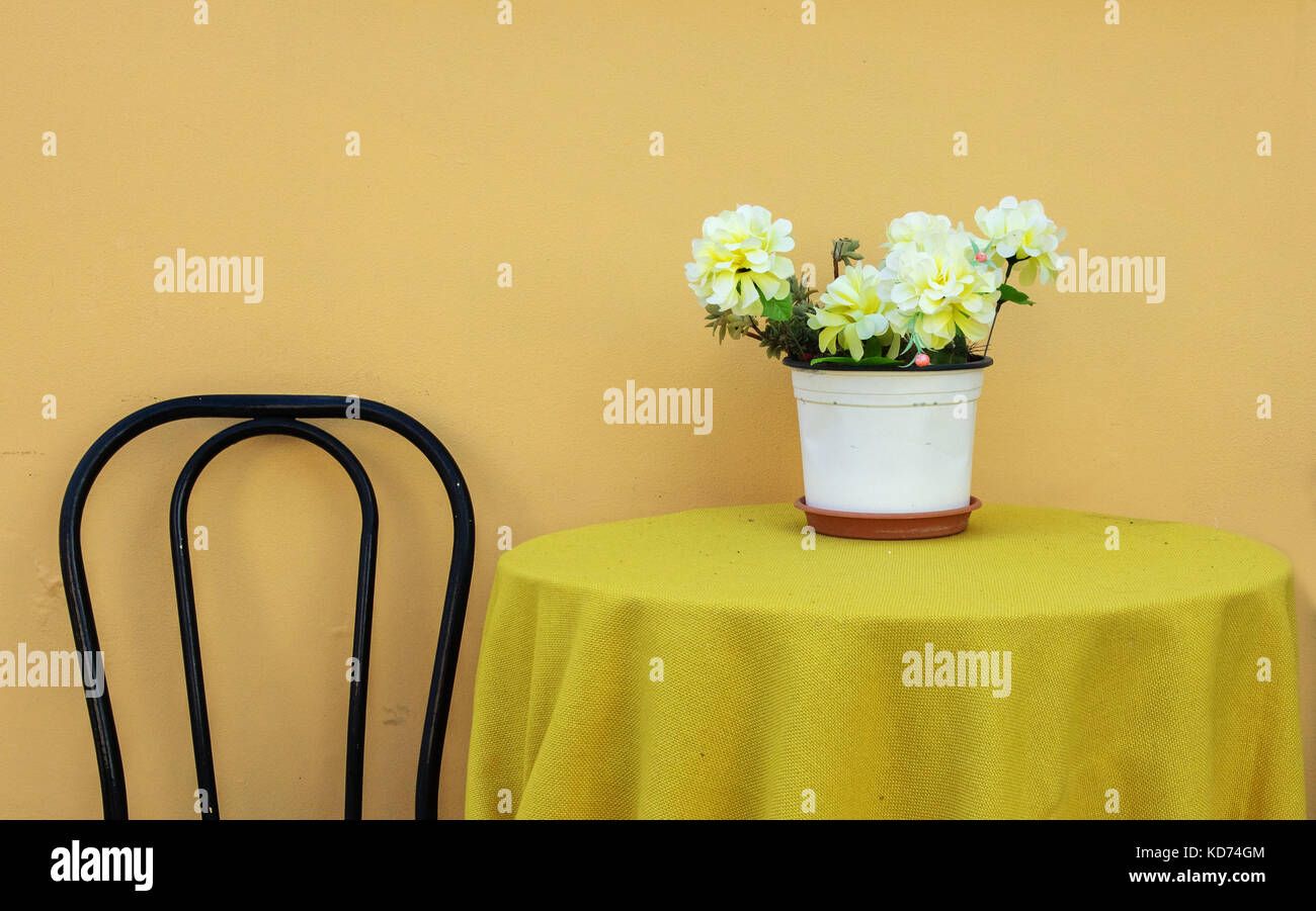 Table with flowers and single chair with a yellow theme on the island of Ithaka in the Ionian Islands of Greece Stock Photo