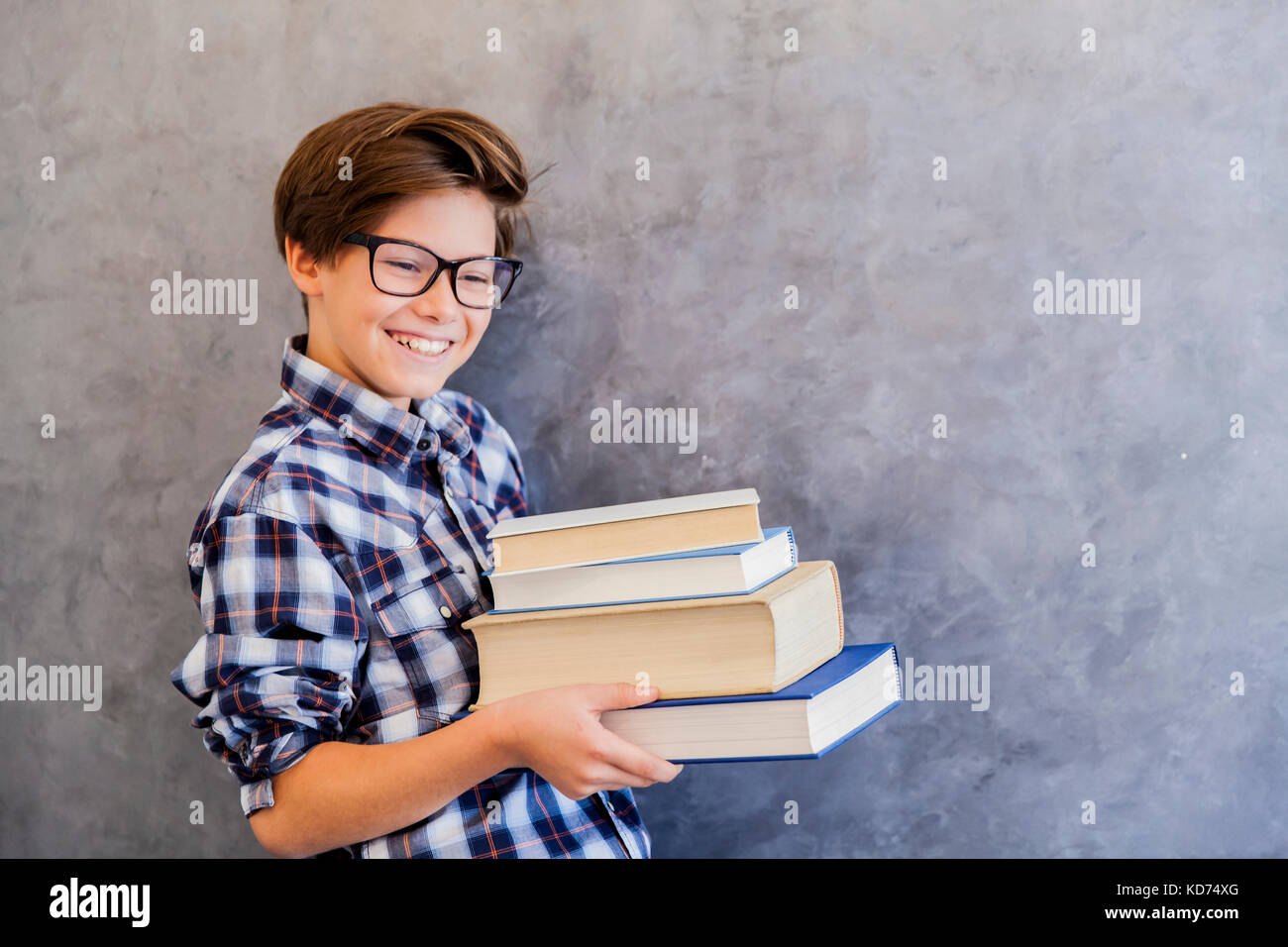 Cute teenage school boy holding books against wall Stock Photo - Alamy