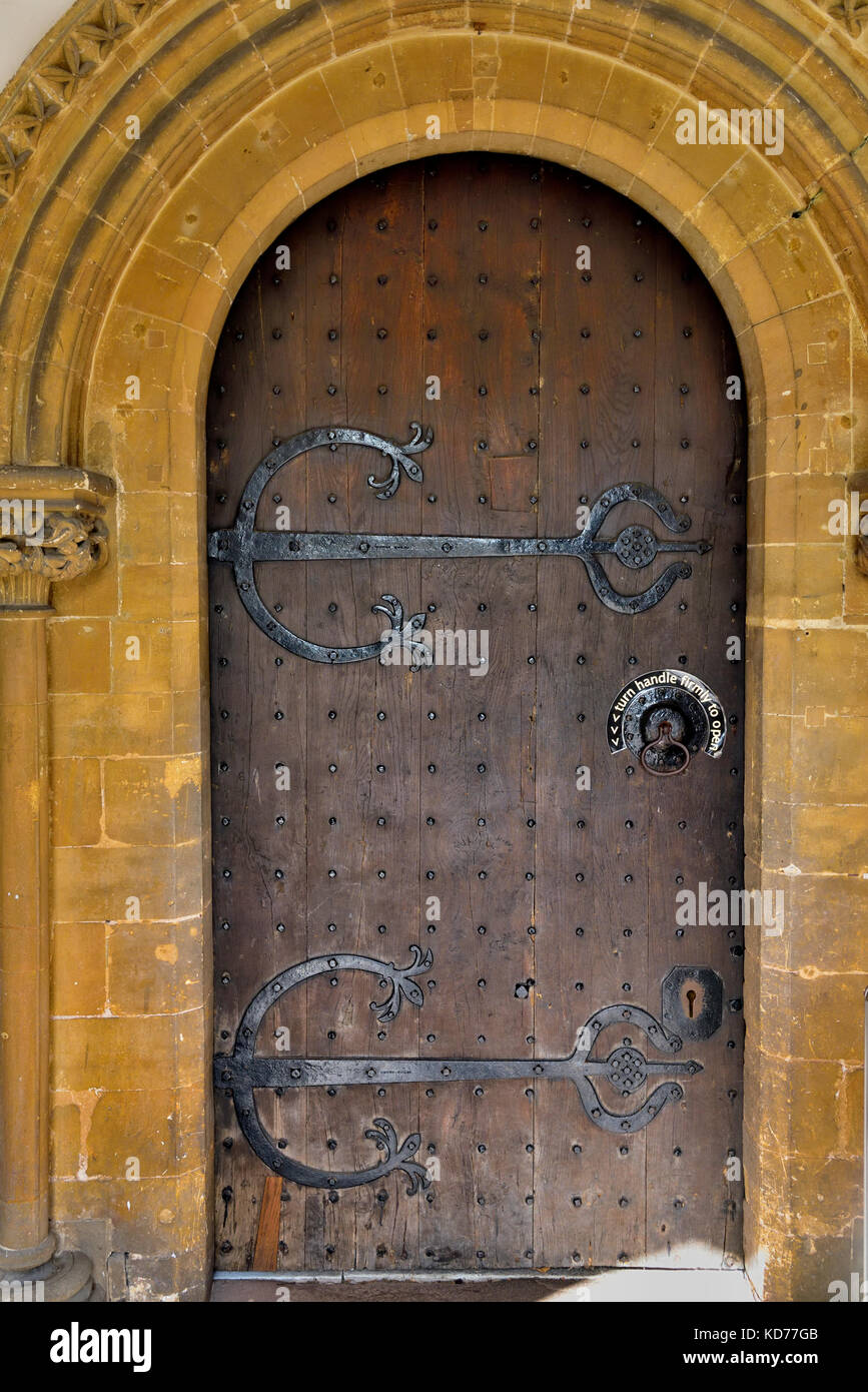 Old heavy wooden door with ornate large hinges Stock Photo