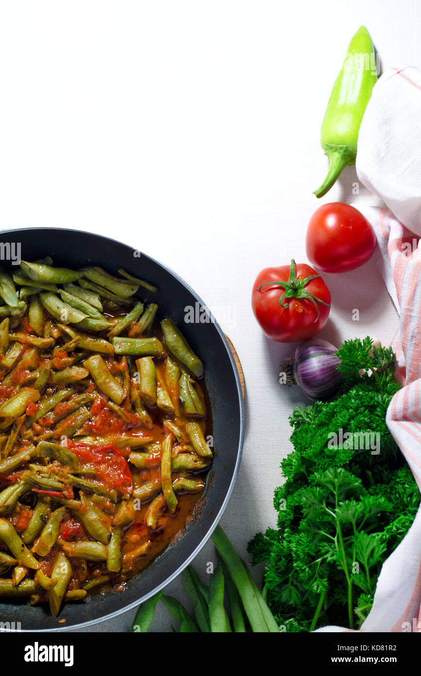 green beans with tomatoes lobio souce in Frying pan on white background Stock Photo