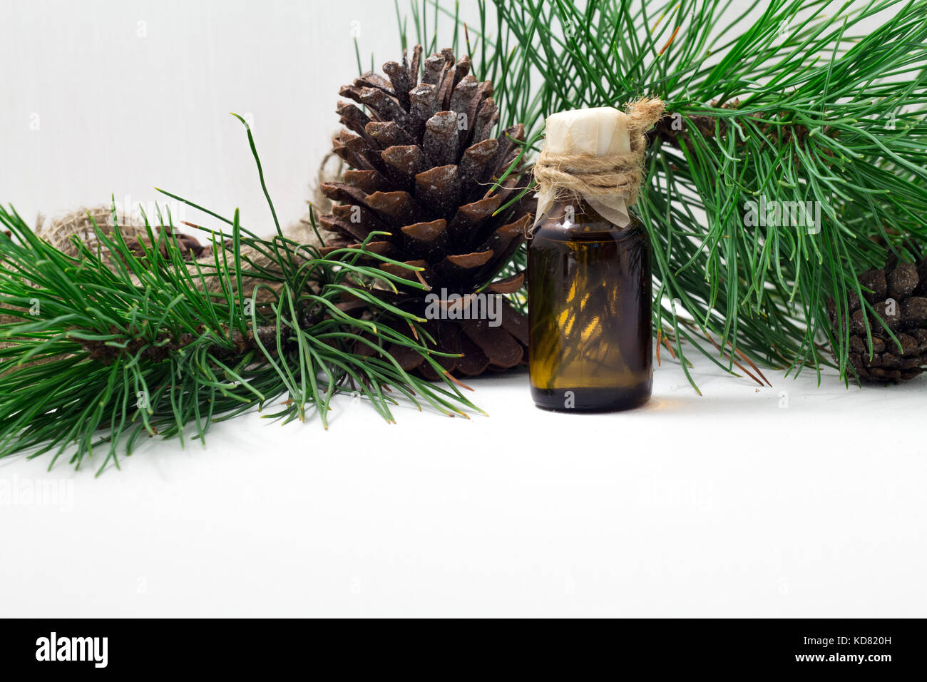 The cedar oil in a glass bottle on a white wooden background. Source of essential fatty acids for healthy nutrition Stock Photo