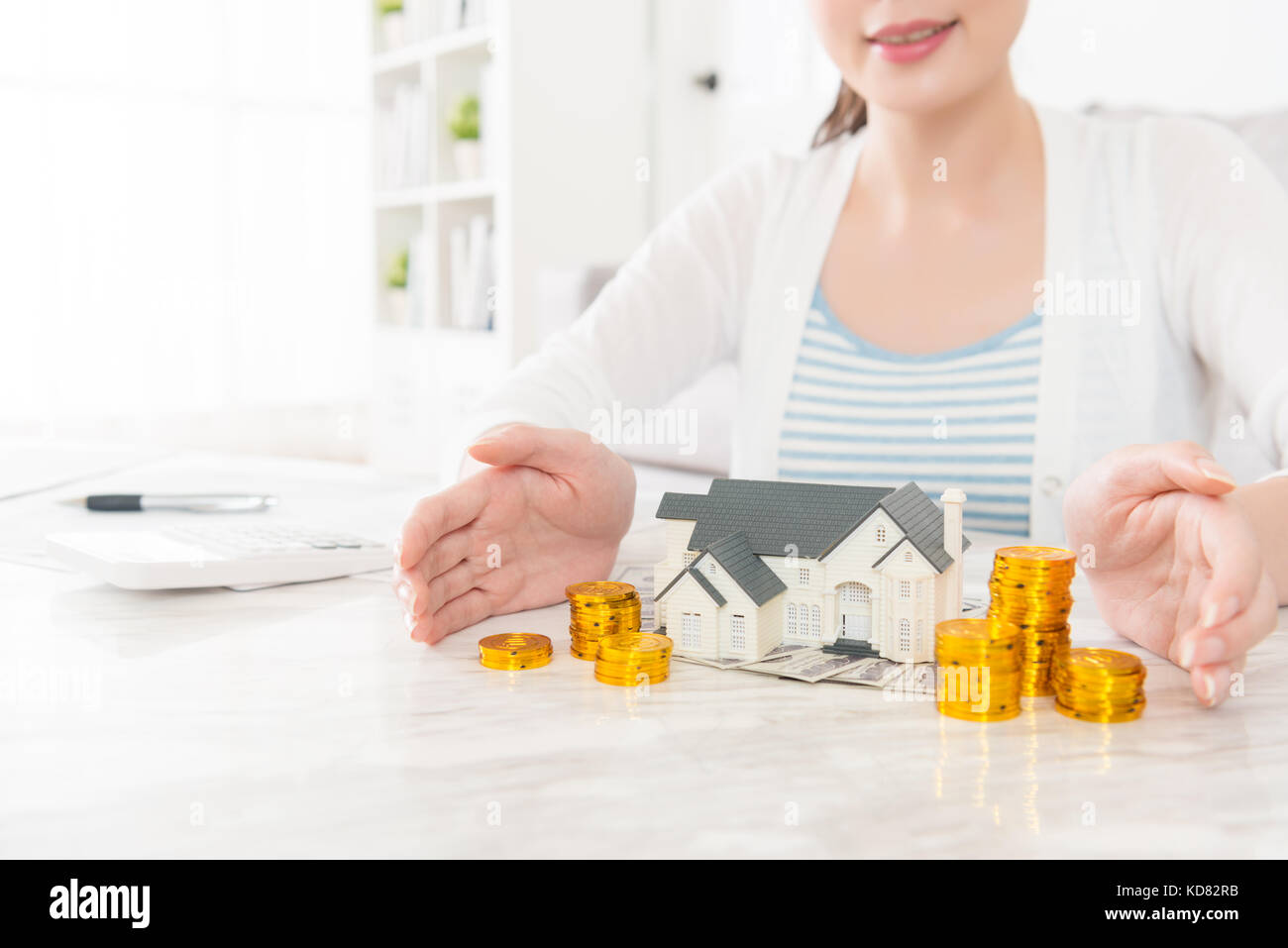 sweet smiling lady showing house model with gold coin stock displaying using personal saving deposit investment estate concept. Stock Photo