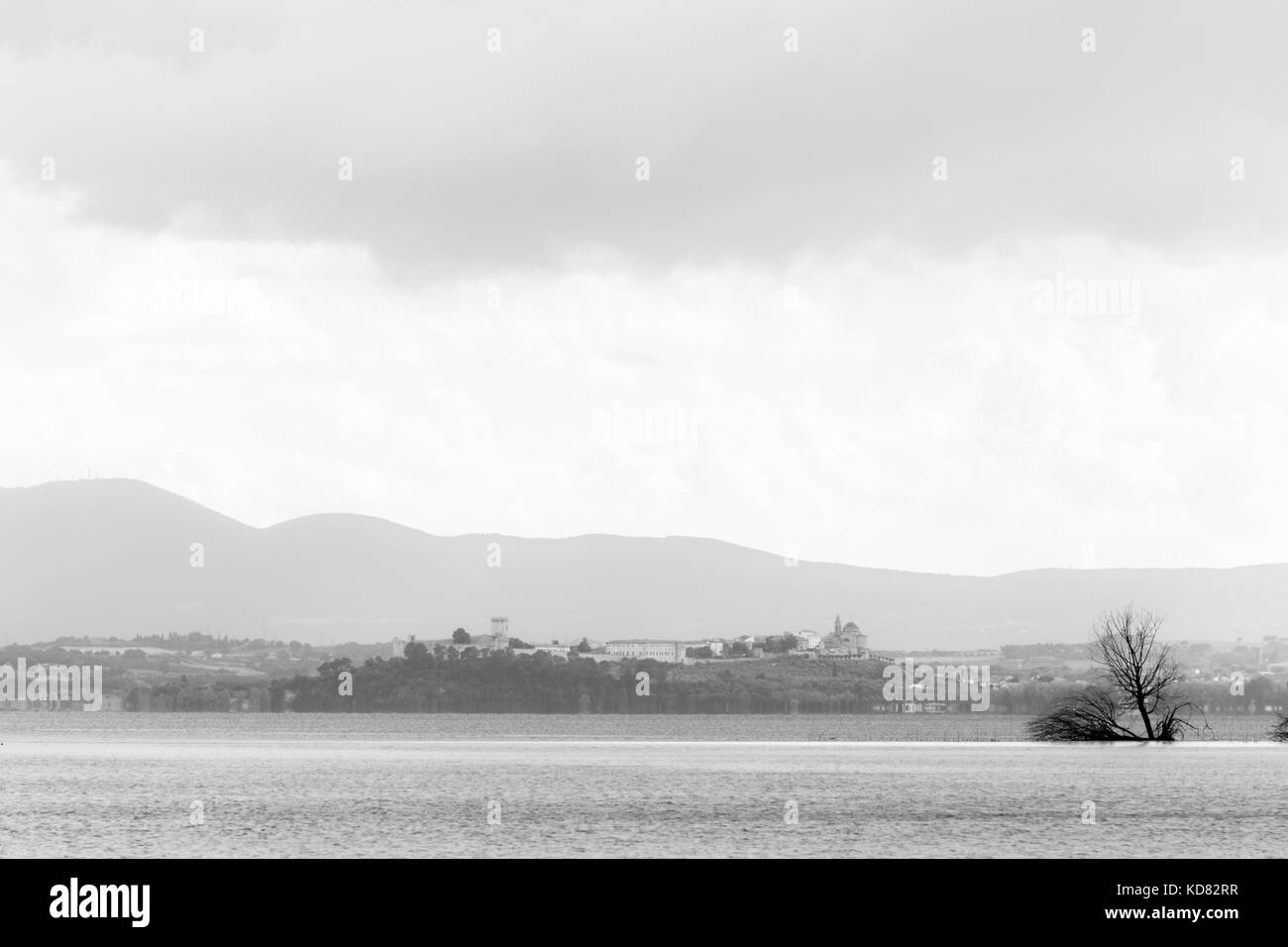 View of Castiglione del Lago town (Umbria, Italy), with Trasimeno lake and trees in the foreground Stock Photo