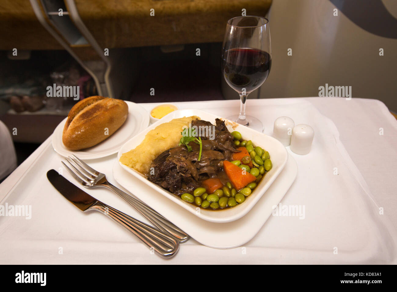 Air Travel Emirates Airlines Business Class food, meal of lamb shank, with carrot fava beans and potato served in A380 cabin Stock Photo