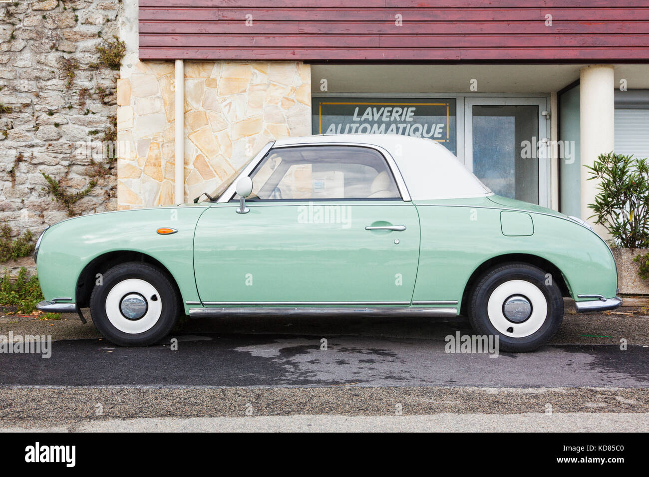 Quiberon, France - September 17, 2017: An emerald green vintage Nissan Figaro in front of a launderette. The Figaro is a retro-styled convertible manu Stock Photo