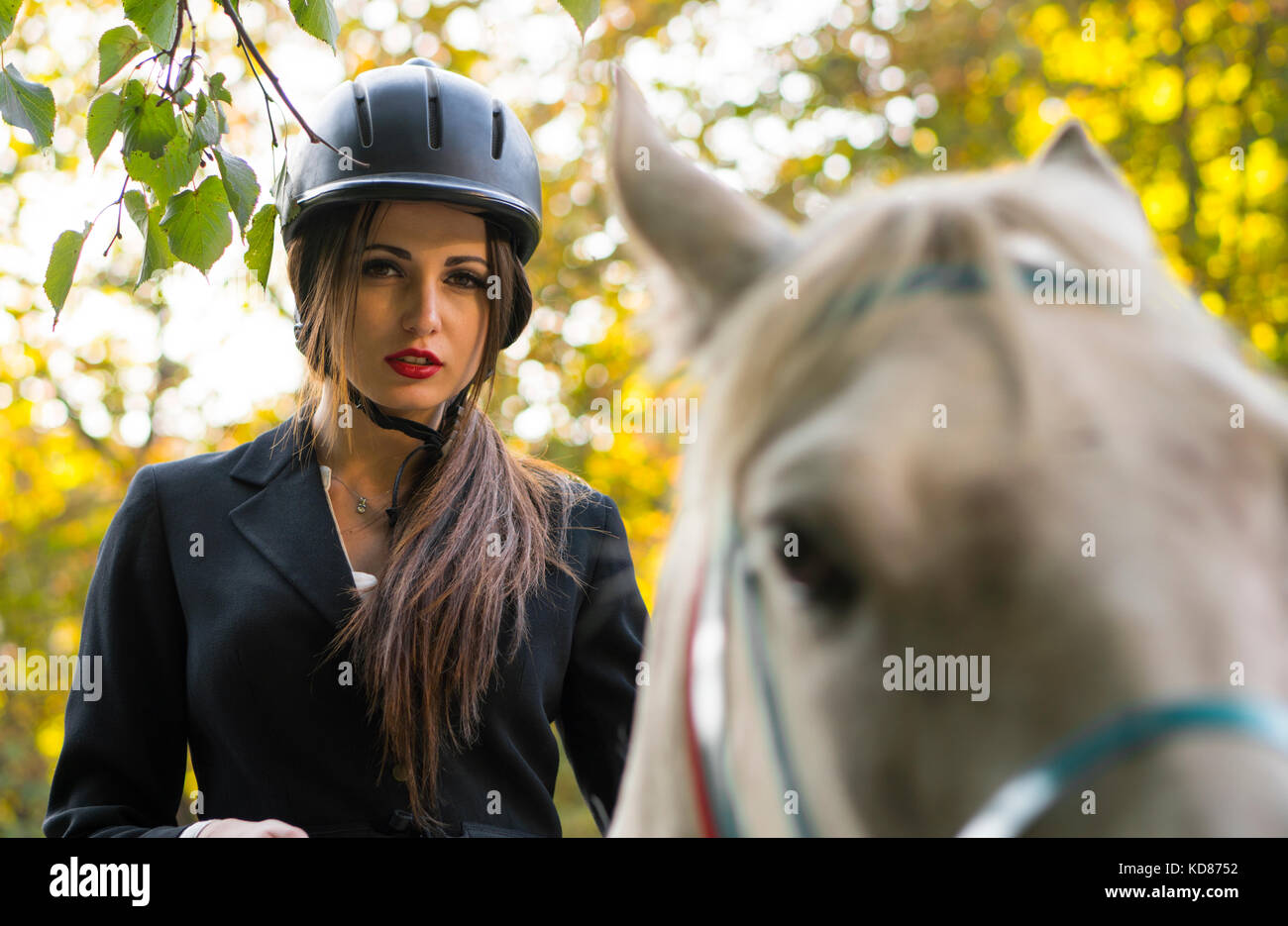 Young brunette beauty jokey girl riding horse in the park Stock Photo -  Alamy