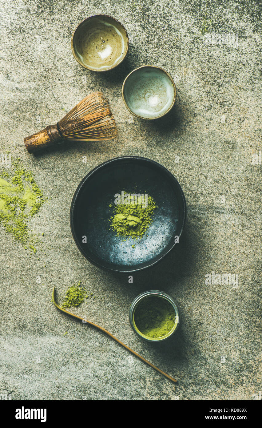Flat-lay of Japanese tools for brewing matcha tea. Matcha powder in tin can, Chashaku spoon, Chasen bamboo whisk, Chawan bowl and ceremony cups over c Stock Photo