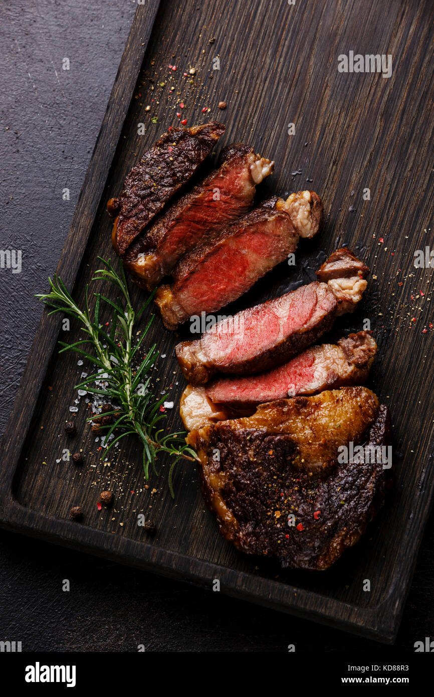Sliced grilled Rib eye steak on dark wooden background close up Stock Photo