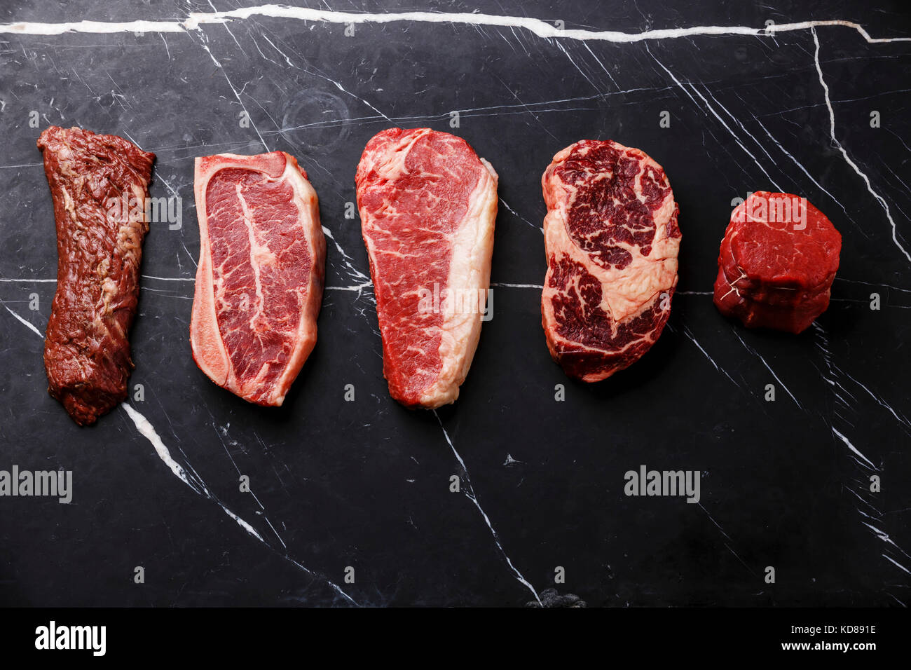 Variety of Raw Black Angus Prime meat steaks Machete, Blade on bone, Striploin, Rib eye, Tenderloin fillet mignon on dark marble background copy space Stock Photo