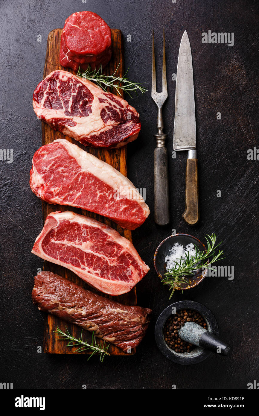 Variety of Raw Black Angus Prime meat steaks Tenderloin fillet mignon, Rib eye, Striploin, Blade, Machete on wooden board and seasoning Stock Photo