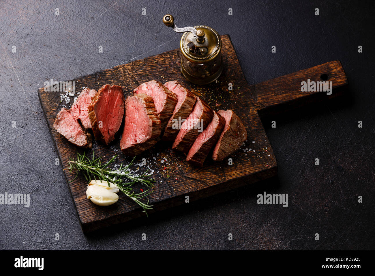 Sliced tenderloin Steak Roast beef on wooden cutting board on dark