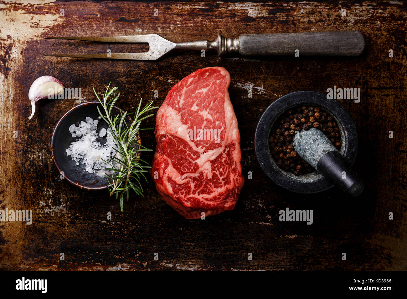 Raw fresh marbled meat Steak Rib eye Black Angus, seasoning and fork on dark metal background Stock Photo