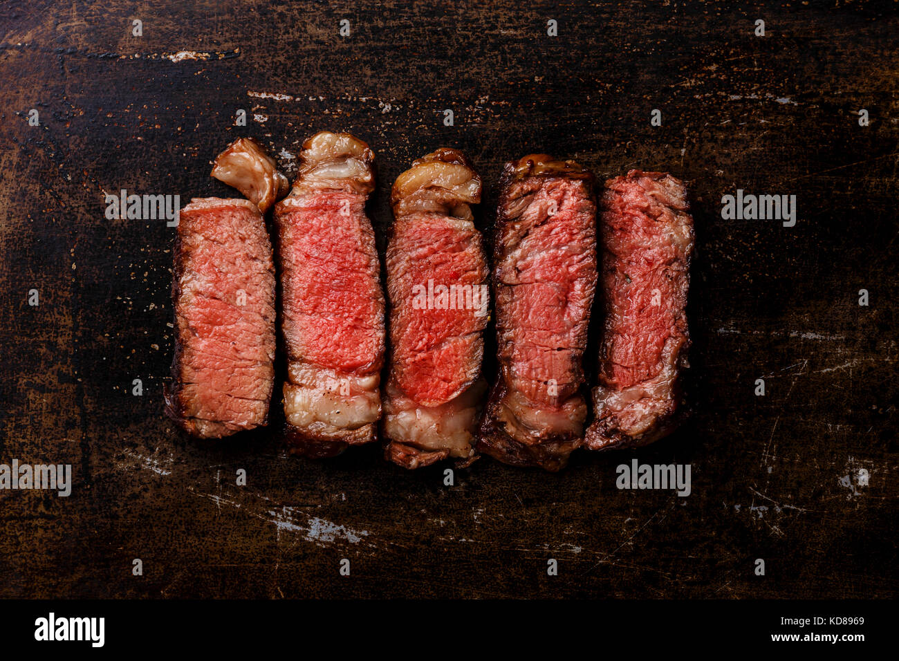 Slices of grilled meat barbecue steak Rib eye medium rare on dark metal background Stock Photo