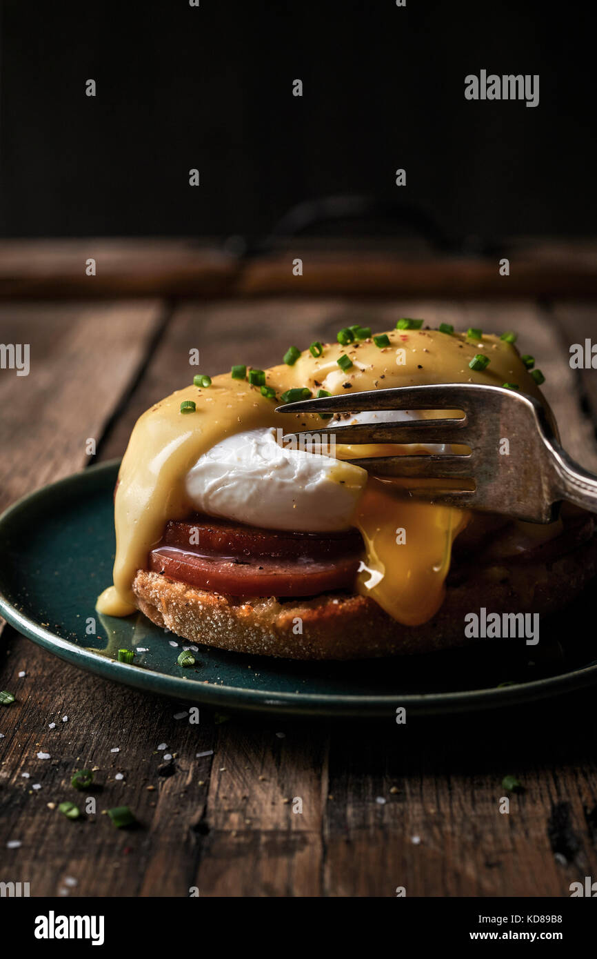 Close-up image of eggs benedict on a rustic wood surface. Stock Photo