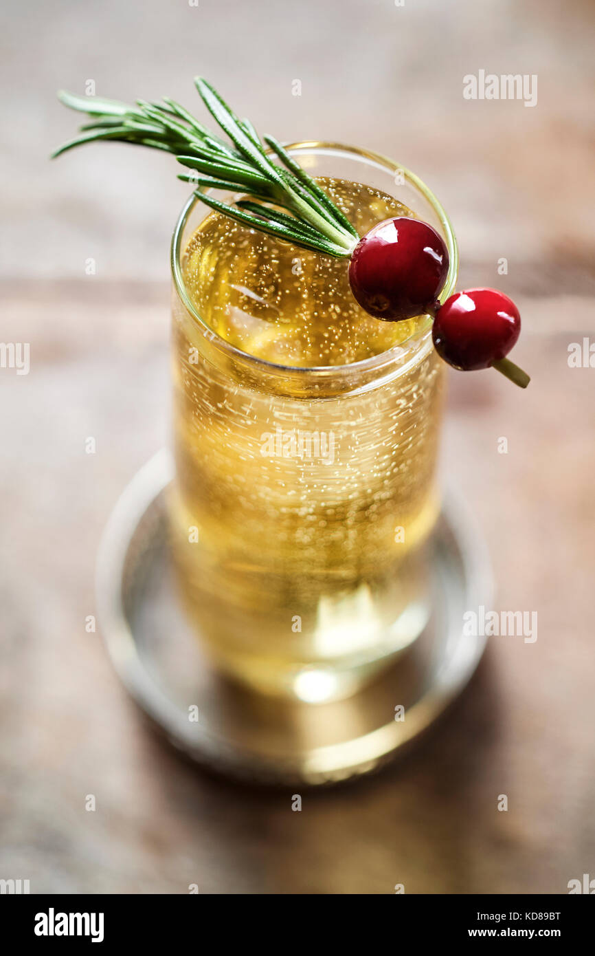 Beautiful champagne drink bubbling in stemless flute with a rosemary and cranberry garnish. Stock Photo