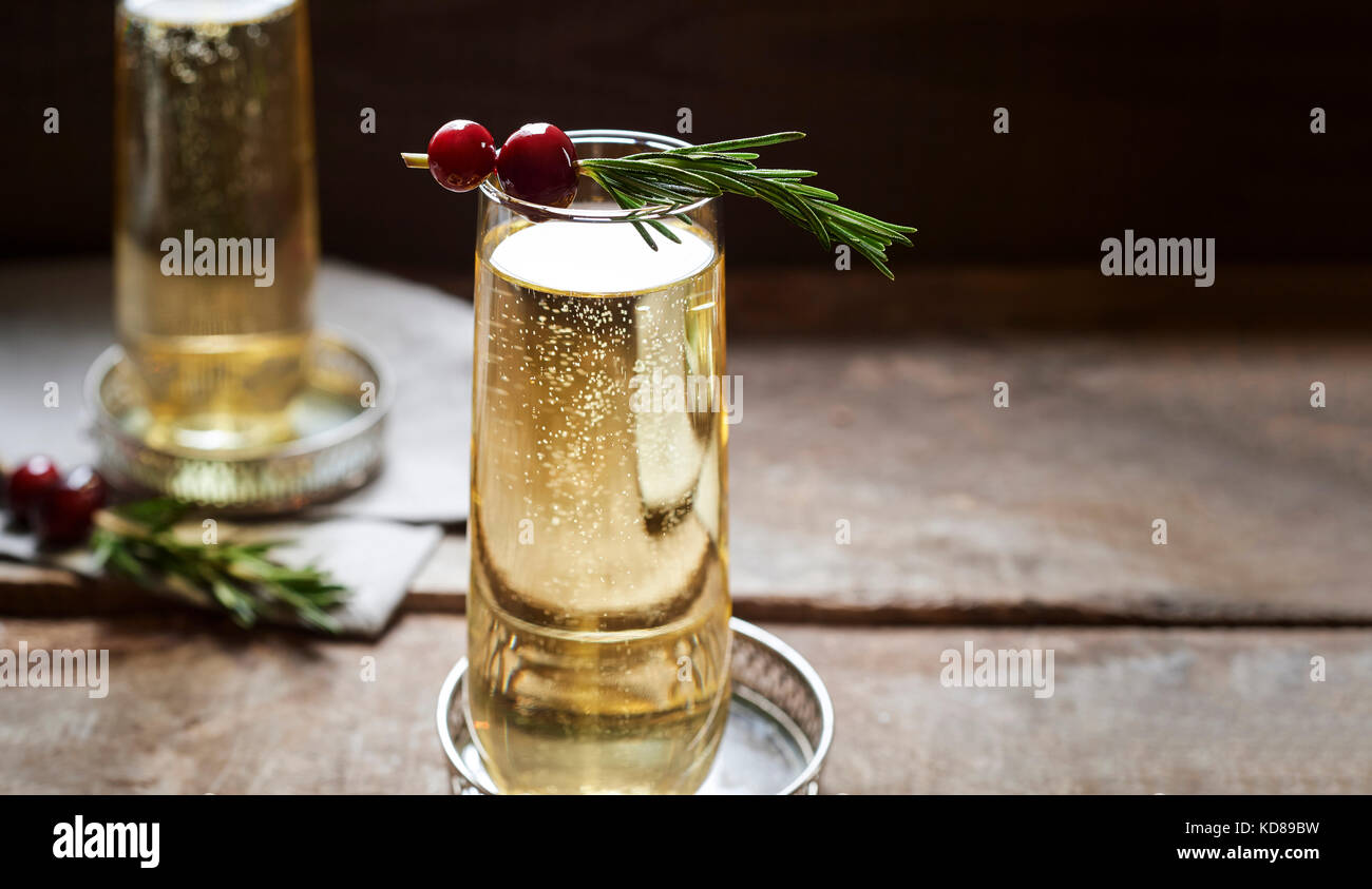 2 Champagnes in elegant stemless flutes with rosemary and cranberry garnishes. Stock Photo