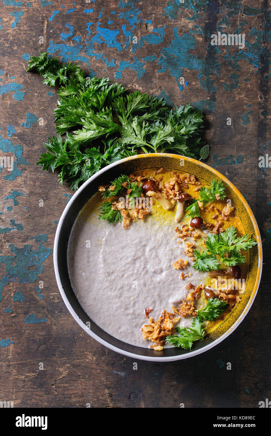 Mushroom cream soup in black ceramic bowl served with turmeric powder