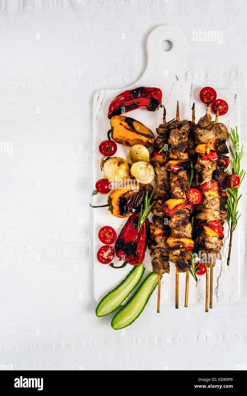Lamb Shish Kebab Served With Grilled Peppers Shallots Fresh Cherry Tomatoes And Cucumber On A White Marble Board Photographed From Top View Stock Photo Alamy