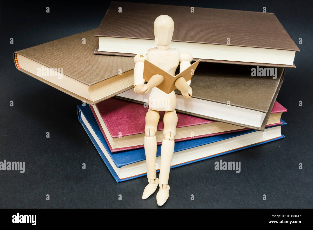 mannequin sitting on a mountain of reading books with a black