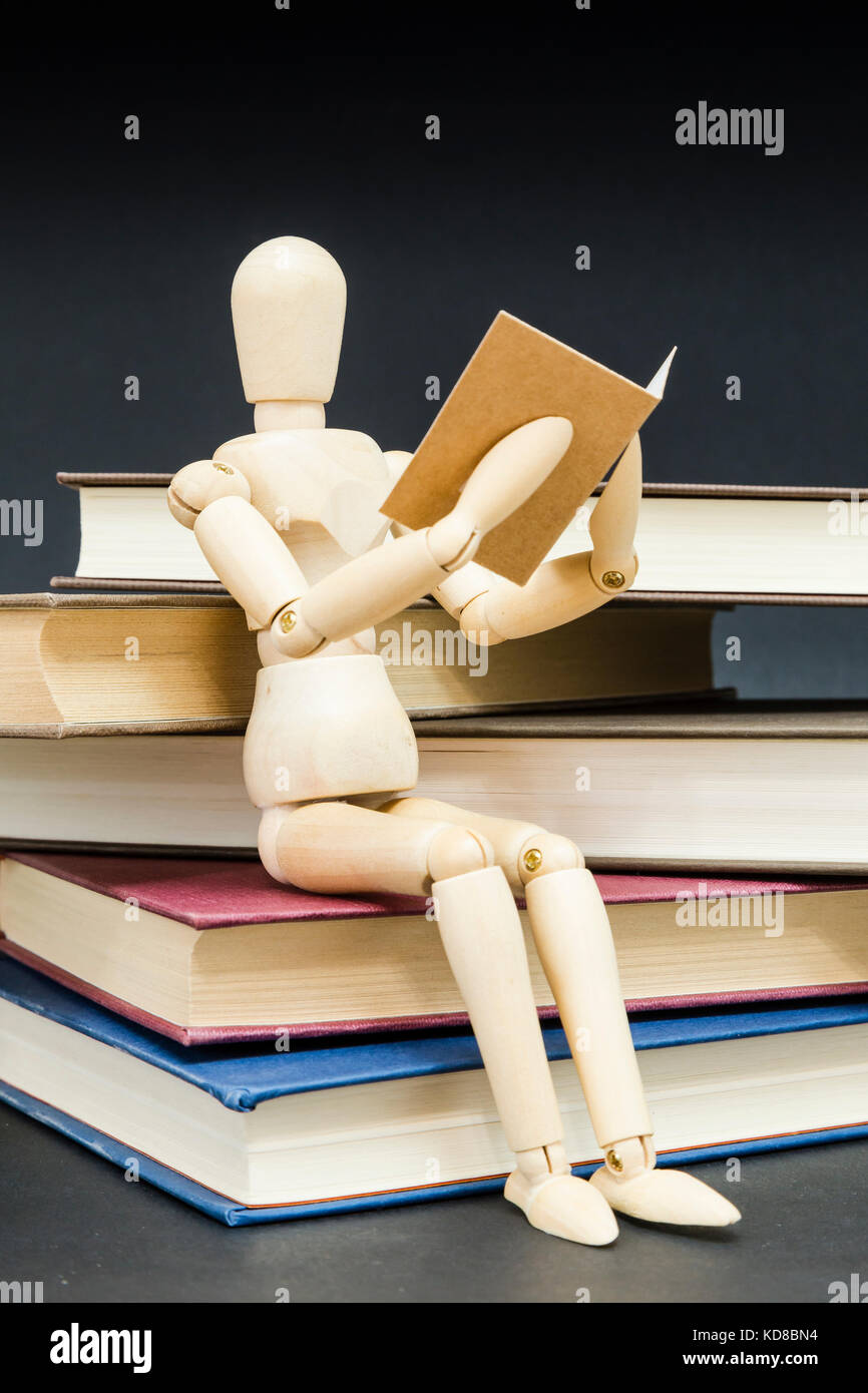 mannequin sitting on a mountain of reading books with a black