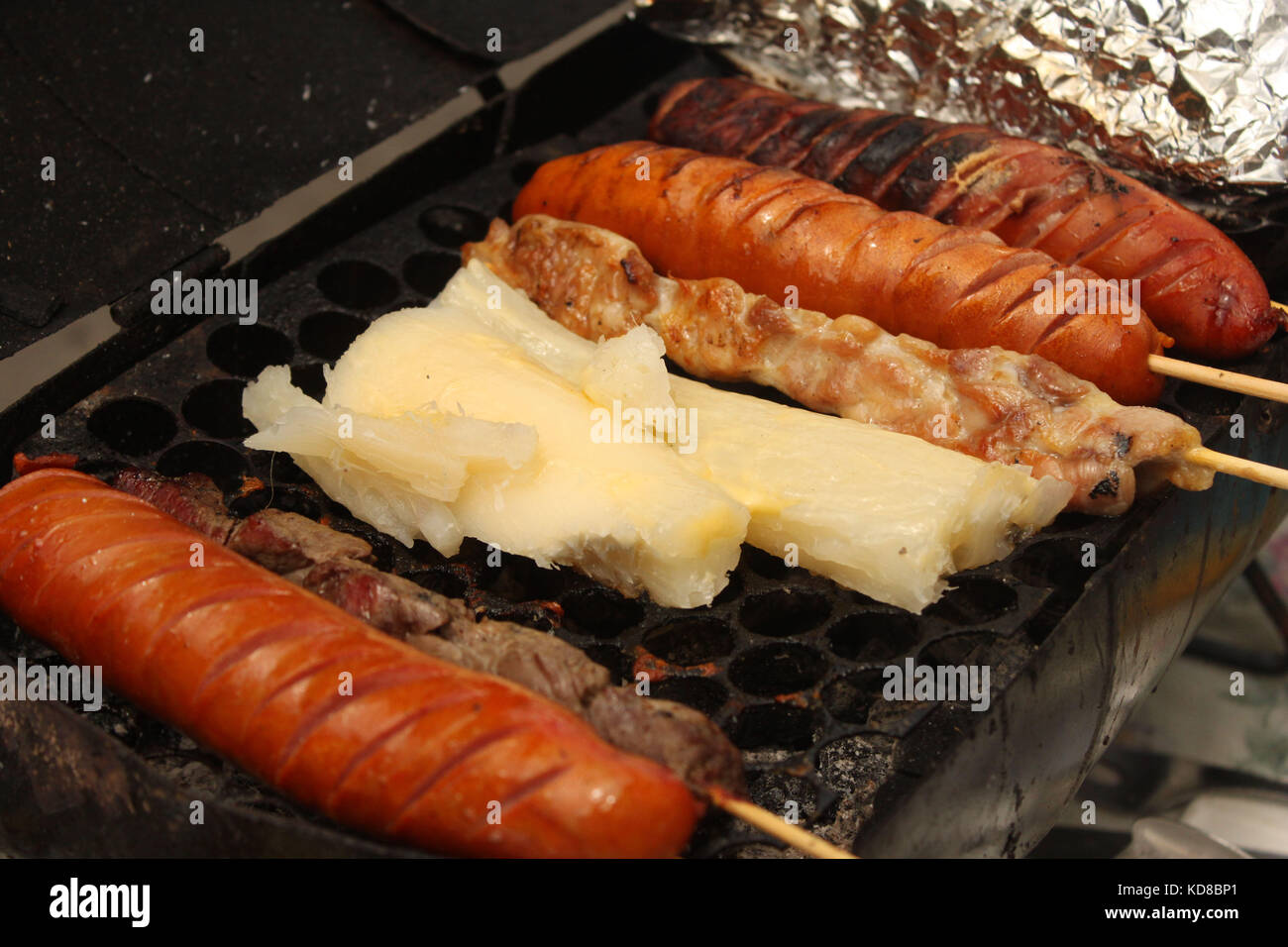 Small street vendor in Rio de Janeiro: grilled sausage, beef, chicken and cassava Stock Photo