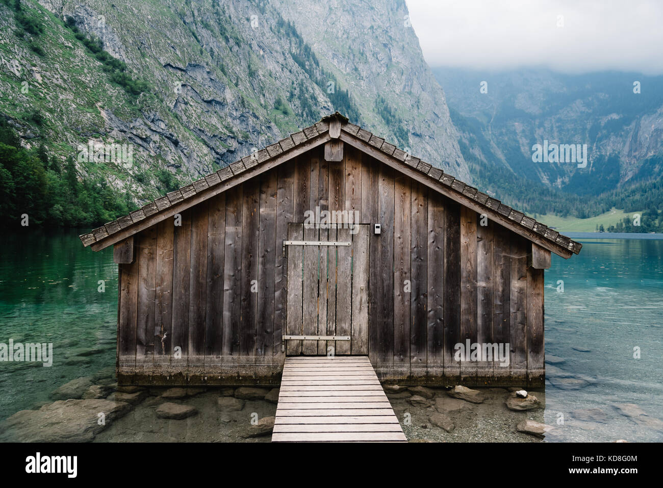 Wooden cottage in beautiful lake in the Alps with misty mood. Stock Photo