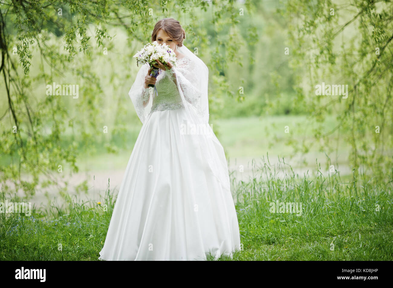 Portrait of a beautiful young bride posing with a bouquet outdoor on ...