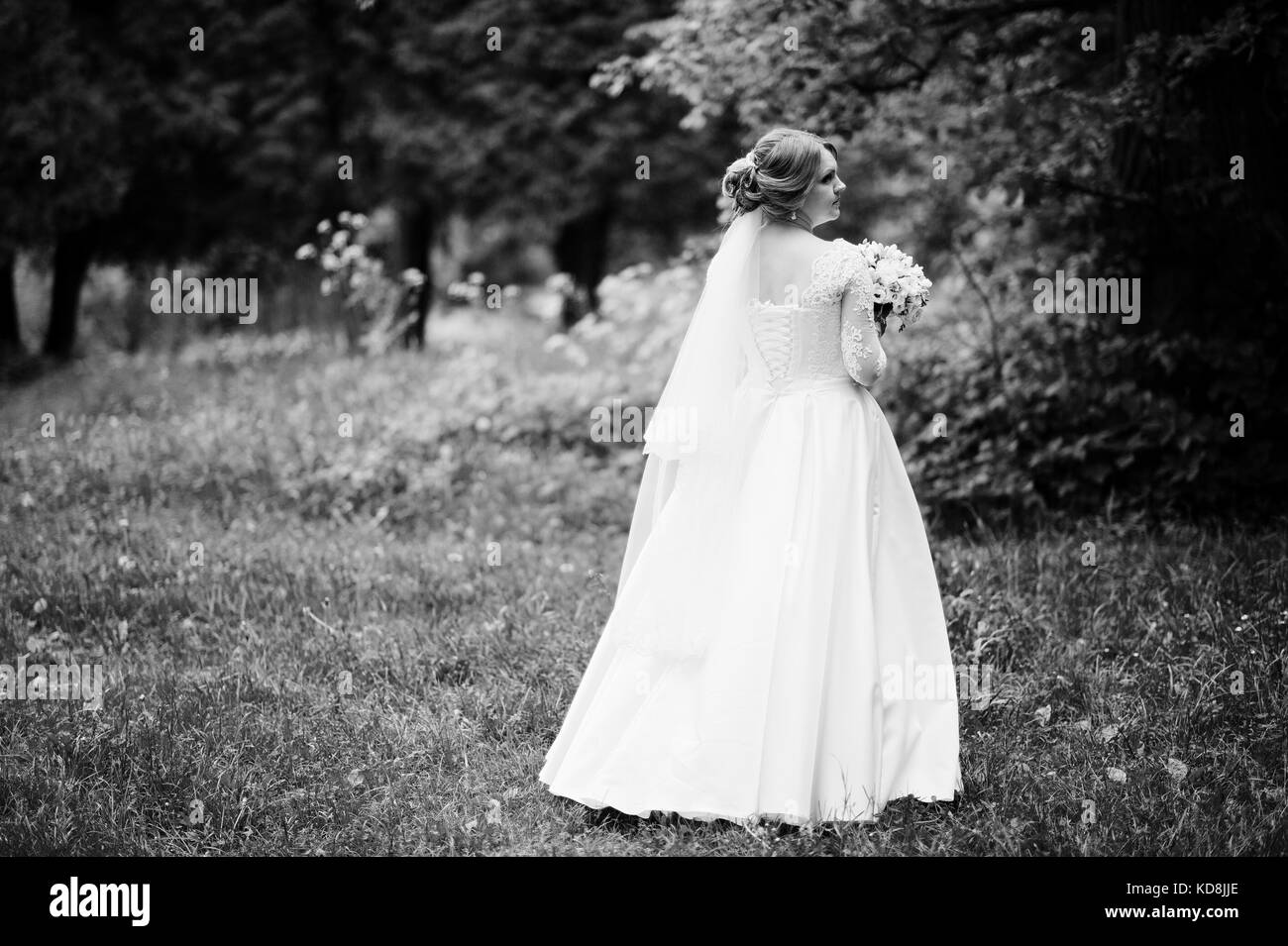 Portrait of a beautiful young bride posing with a bouquet outdoor on ...