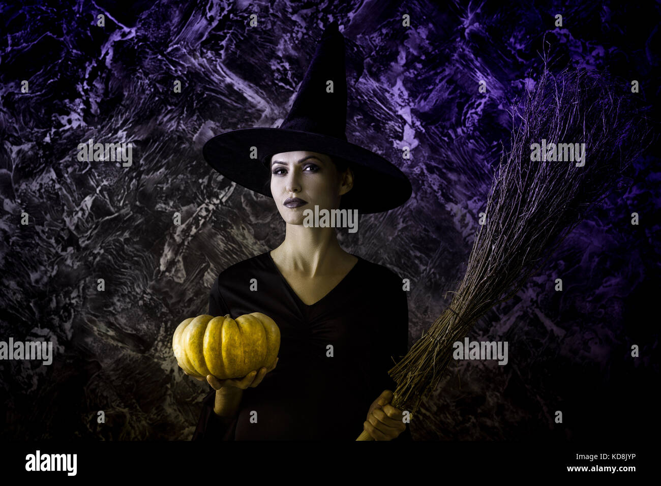 Halloween Witch holding a pumpkin and a broom Stock Photo - Alamy