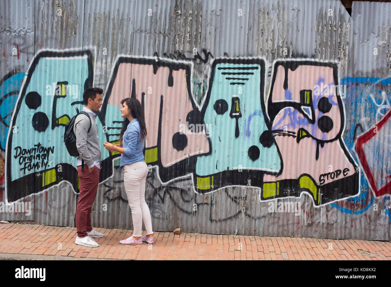 Two people in conversation in front of street art in Bogota, Colombia Stock Photo