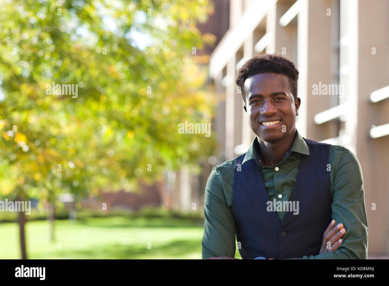A handsome young black male student smiles standing on college campus Stock Photo