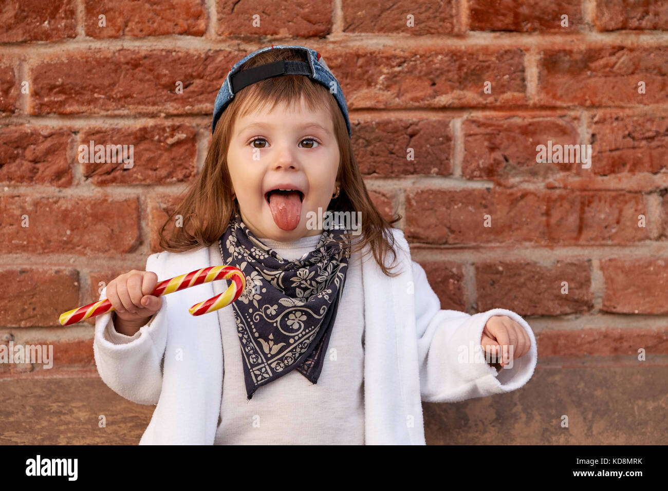 Cute beautiful child eats candy.little girl shows tongue Stock Photo