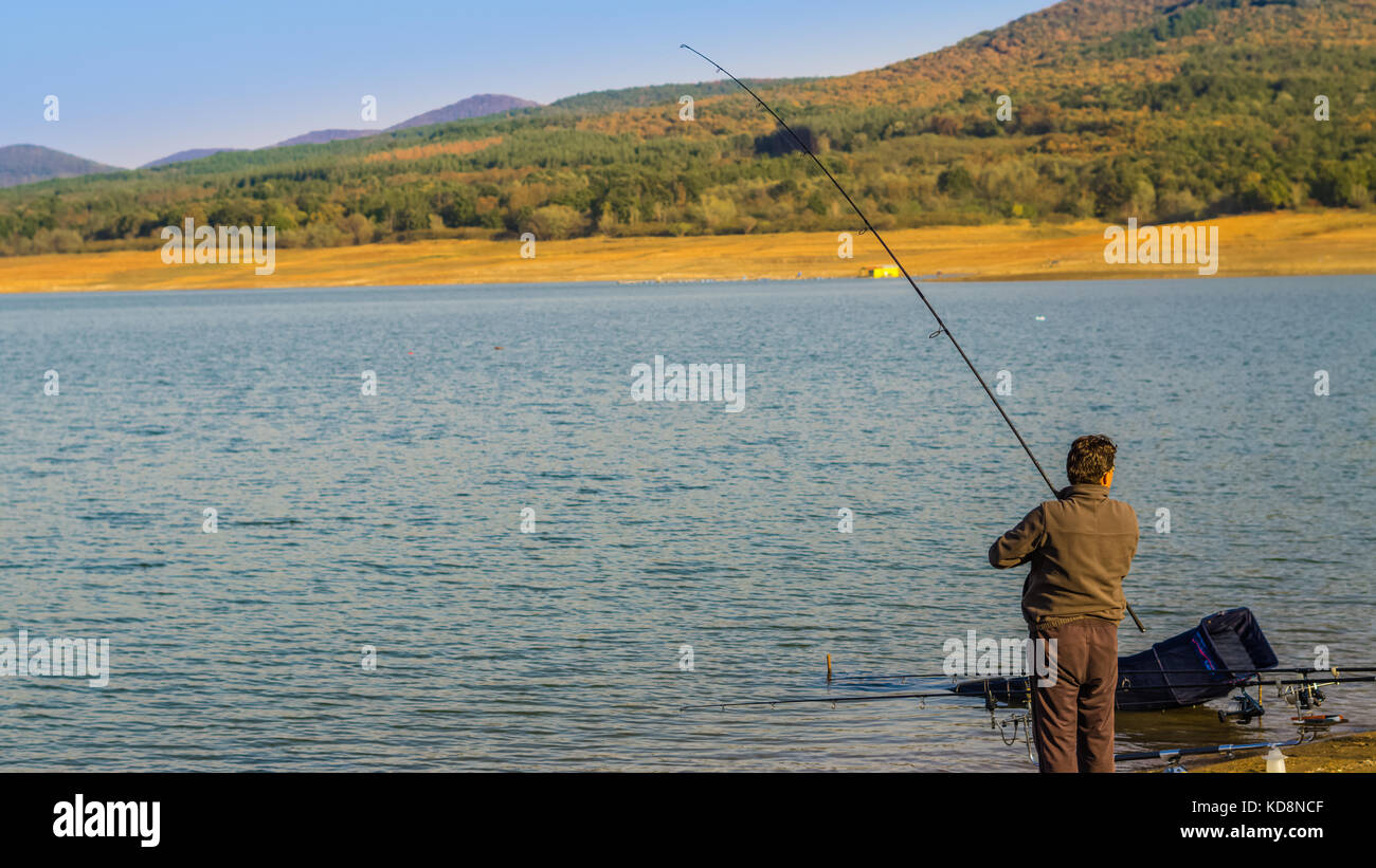 Jrebchevo Dam, Bulgaria a man caught fish on the fishing line trying to get  it out on the shore Stock Photo - Alamy