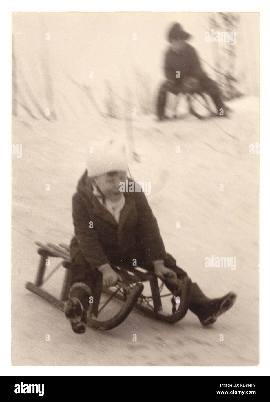 Blurred photograph of children on sledges dated 1963 Stock Photo