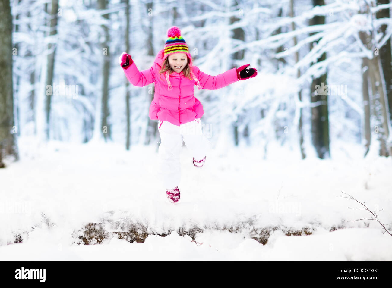 Child playing with snow in winter. Little girl in colorful jacket and ...