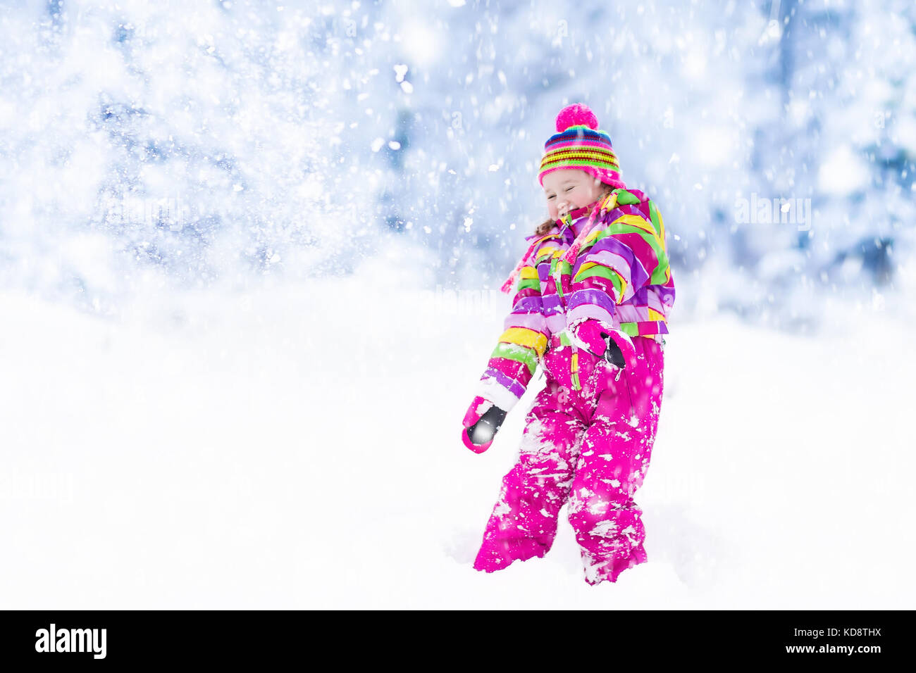 Child playing with snow in winter. Little girl in colorful jacket and ...