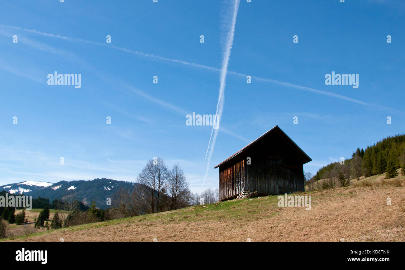 Aircraft contrail clouds high up in the blue skies over the mountain exclave quadripoint border village of Jungholz, Tirol, Austria. Stock Photo