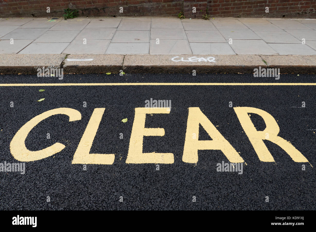 The word 'Clear' stencilled on the road and sprayed on the kerb Stock Photo
