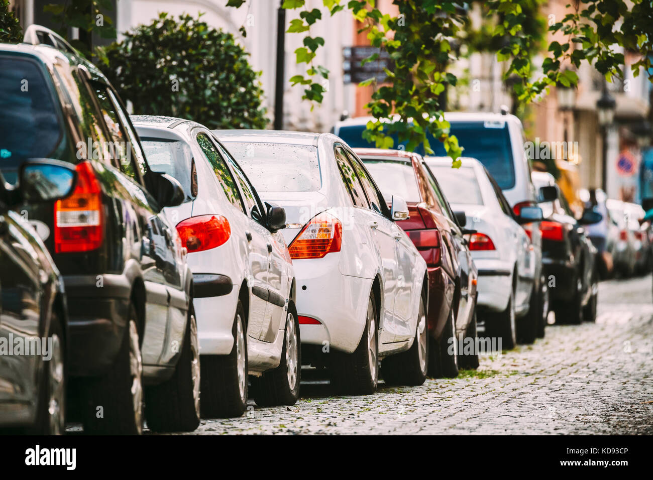 Many Cars Parked On Street In European City In Sunny Summer Day. Row Of City Cars Stock Photo