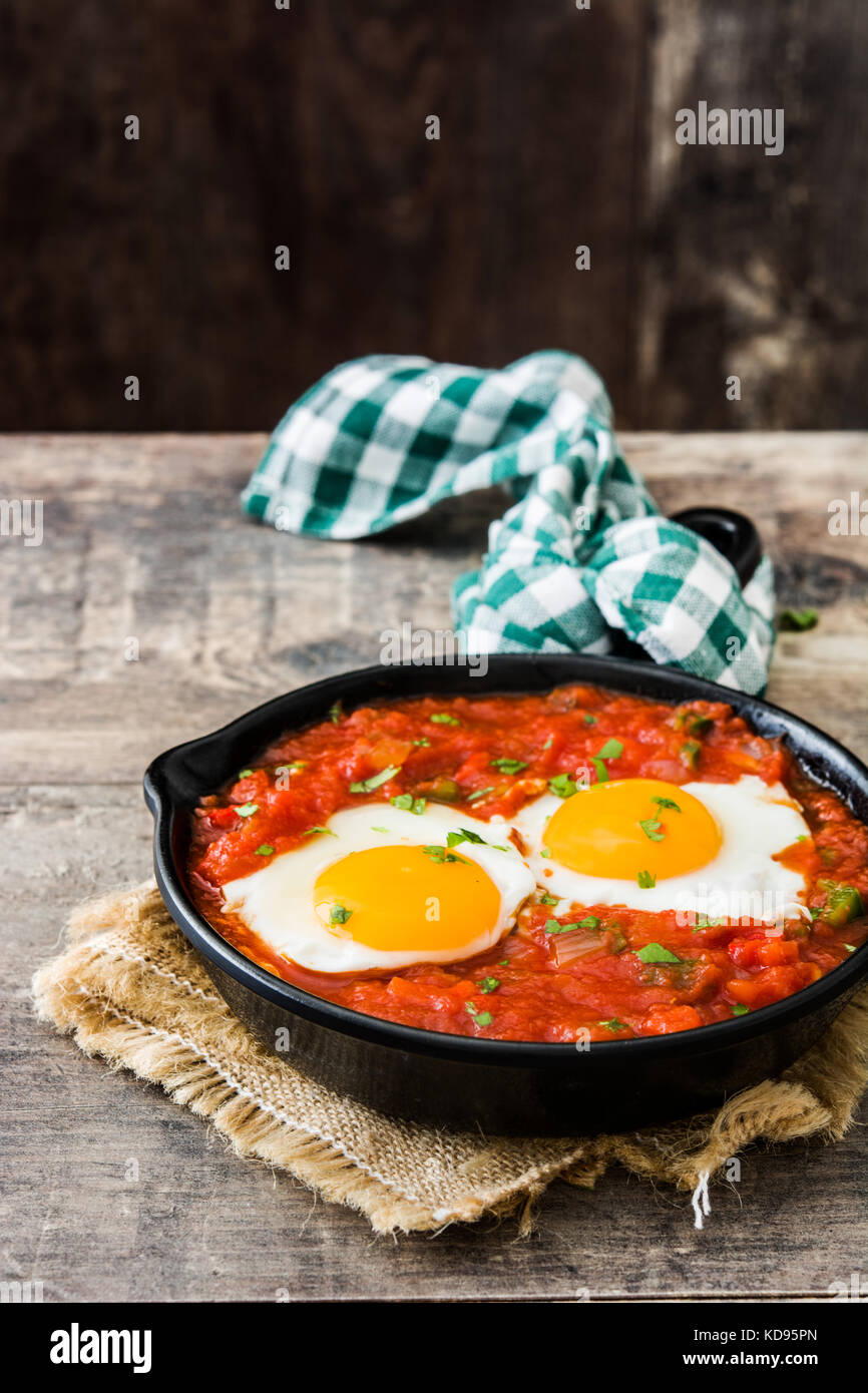Mexican breakfast: Huevos rancheros in iron frying pan on wooden table Stock Photo