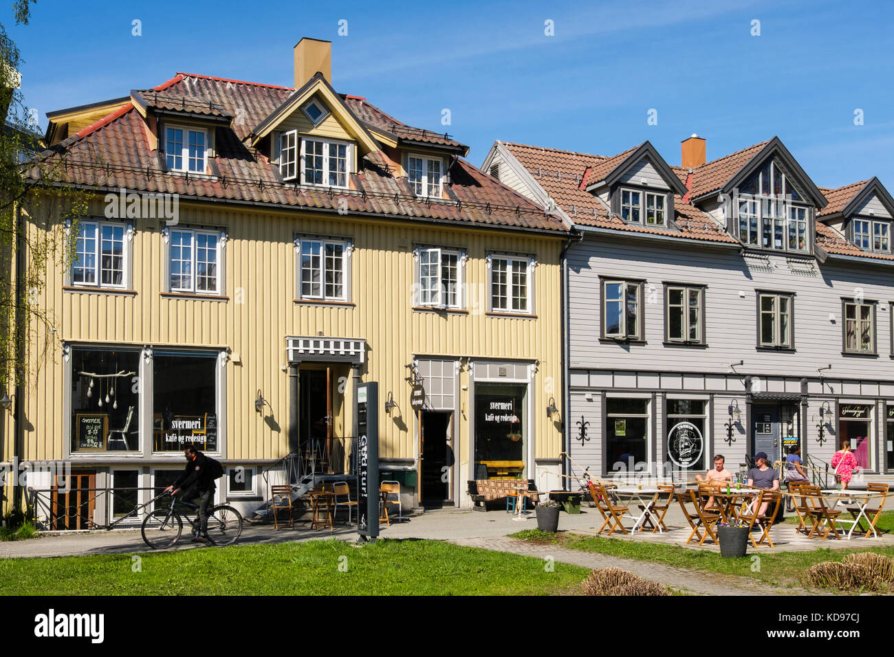 Street cafe and wooden Norwegian buildings with people outside enjoying sunshine in city centre in summer. Tromso, Troms county, Norway, Scandinavia Stock Photo