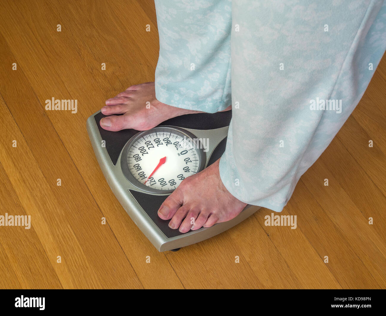 Woman in pajamas weighing herself Stock Photo