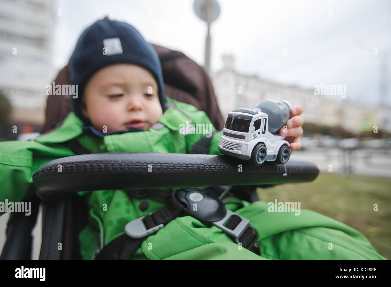 Child in stroller playing with car Stock Photo