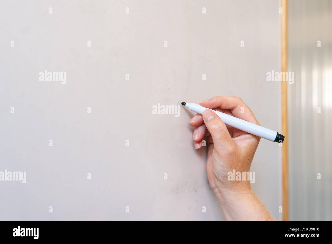 Female hand writing on whiteboard with felt tip pen Stock Photo
