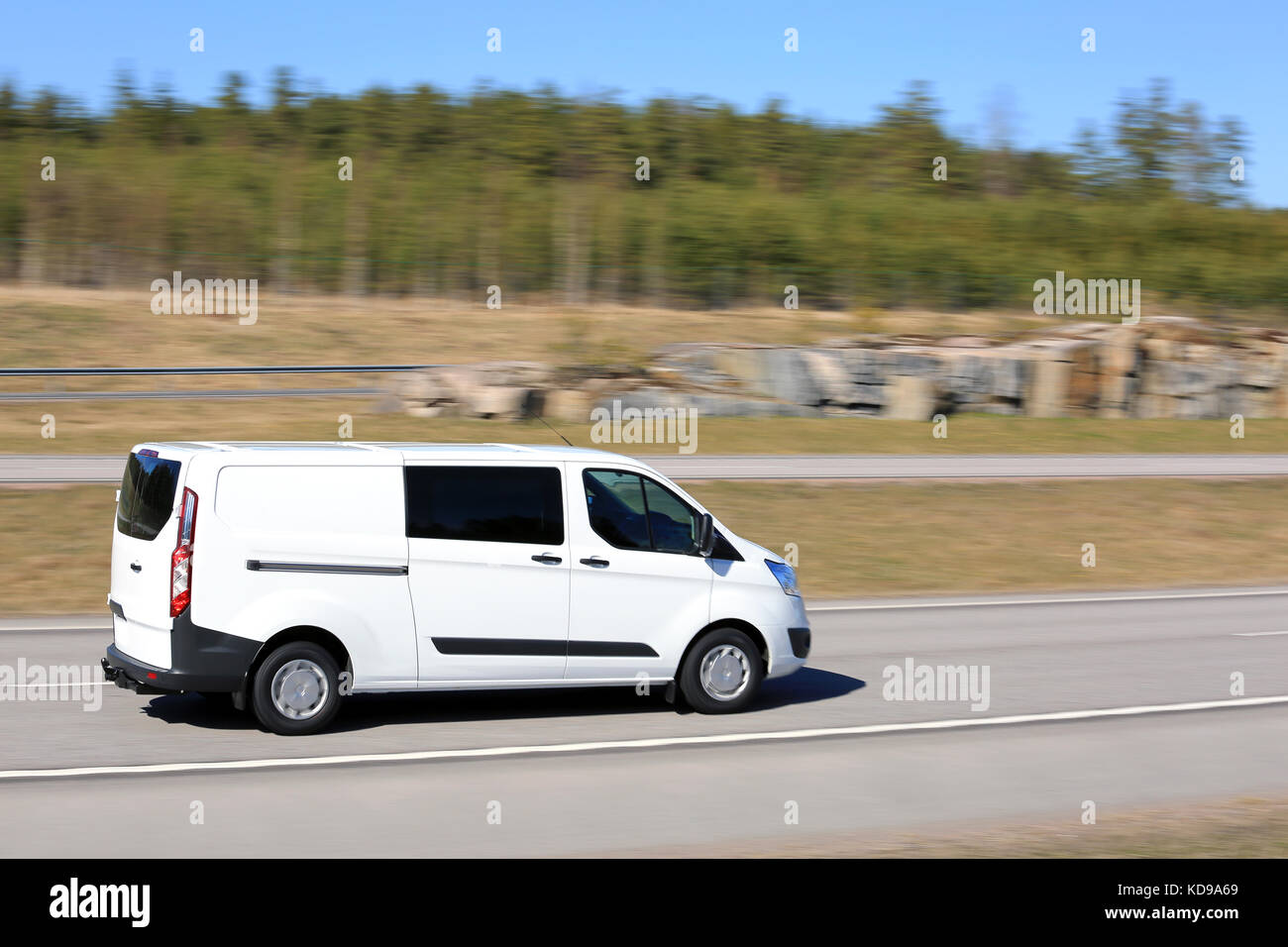 Empty freeway on a beautiful day of spring with white van at speed, blurred background with in camera panning effect. Stock Photo