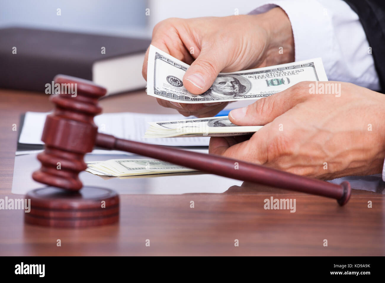 Close-up Of Male Judge's Hand Counting Banknote In Front Of Mallet Stock Photo