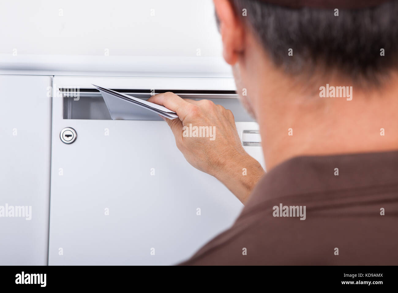 Close-up Of Postman Putting Letters In Mailbox Stock Photo