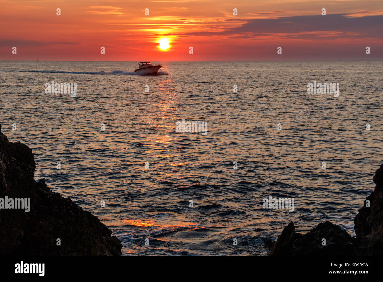 A speedboat is homeward bound as the sunsets over Punta del Capo Sorrento, Italy. Stock Photo